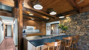 Eine Küche mit Holzausstattung, einer Steinwand und einer Bar mit Hockern.