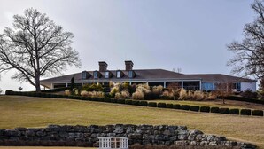 A large, two-story house with a sloped roof, stone retaining wall, and a well-maintained lawn. - Birdie's Bliss 2BR Condo Sleeps 6! (Lake Ozark)