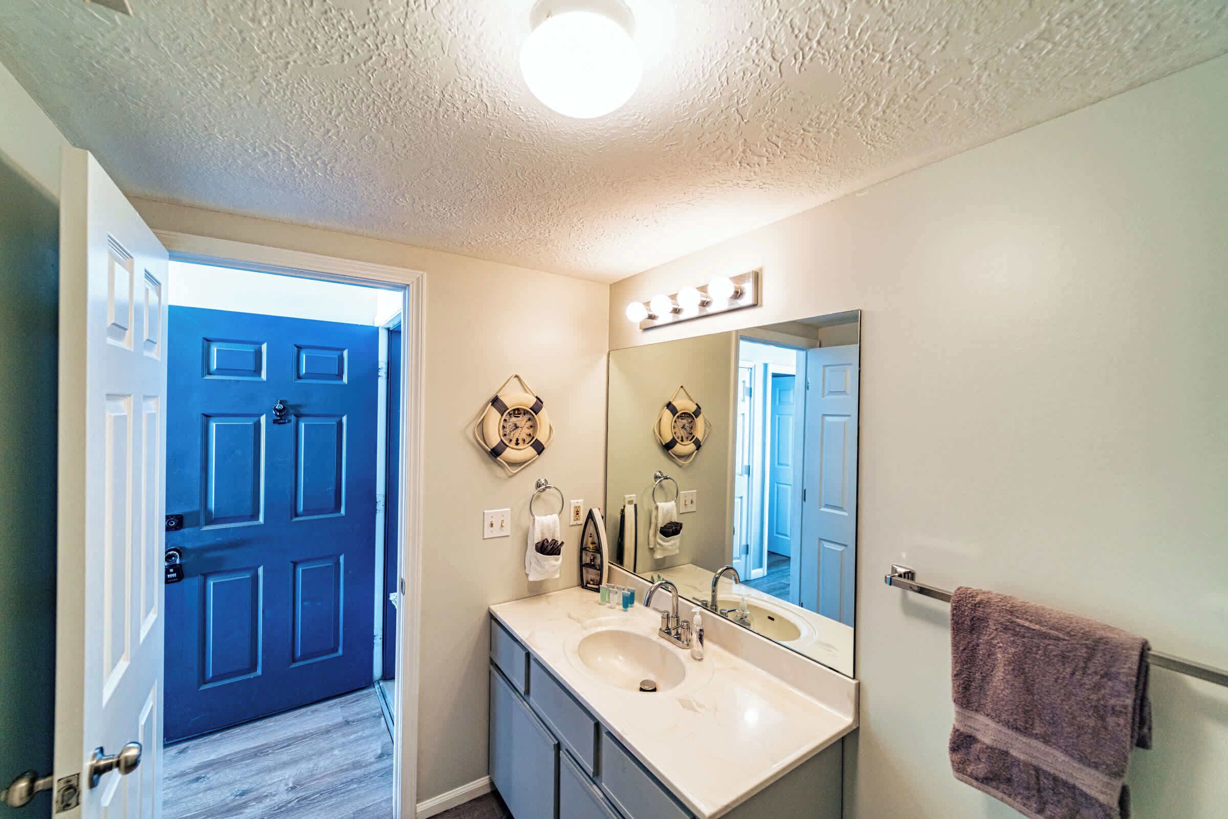 A bathroom with a large mirror, vanity, and a towel rack.