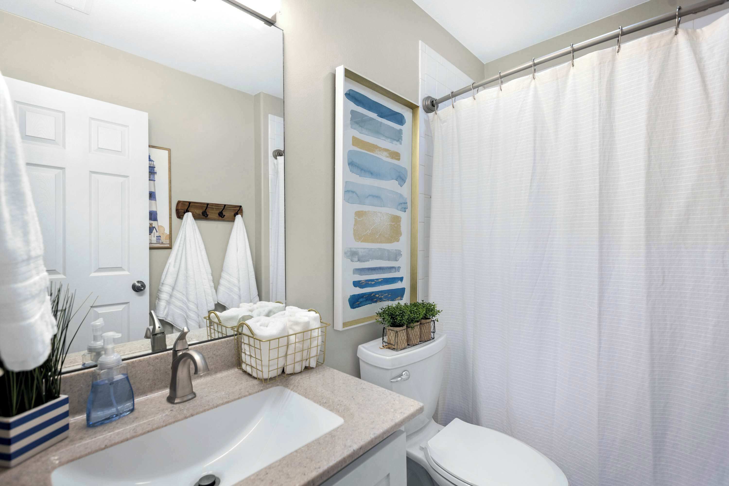 Een badkamer met een wastafel, spiegel, toilet en douchegordijn.