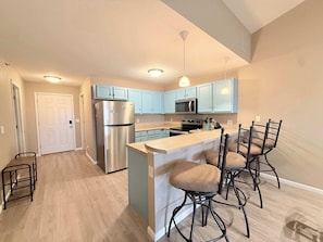 A modern kitchen with light blue cabinets, stainless steel appliances, and a central island with bar stools. - Highland Lake View – Incredible Location! (Lake Ozark)