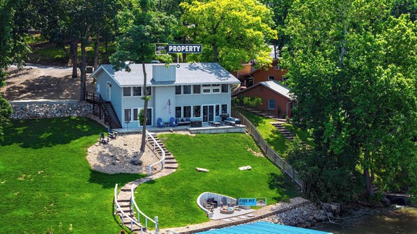 A two-story house with a covered patio, a stone staircase, and a fenced yard.
