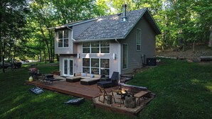 A two-story house with a deck, outdoor seating, and a fire pit. - Treehouse LOZ – Seclusion for 6! (Sunrise Beach)