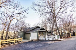 A small, single-story building with a porch and a fenced area. - Serenity Now – Quiet 4 BDR Next to Margaritaville! (Osage Beach)
