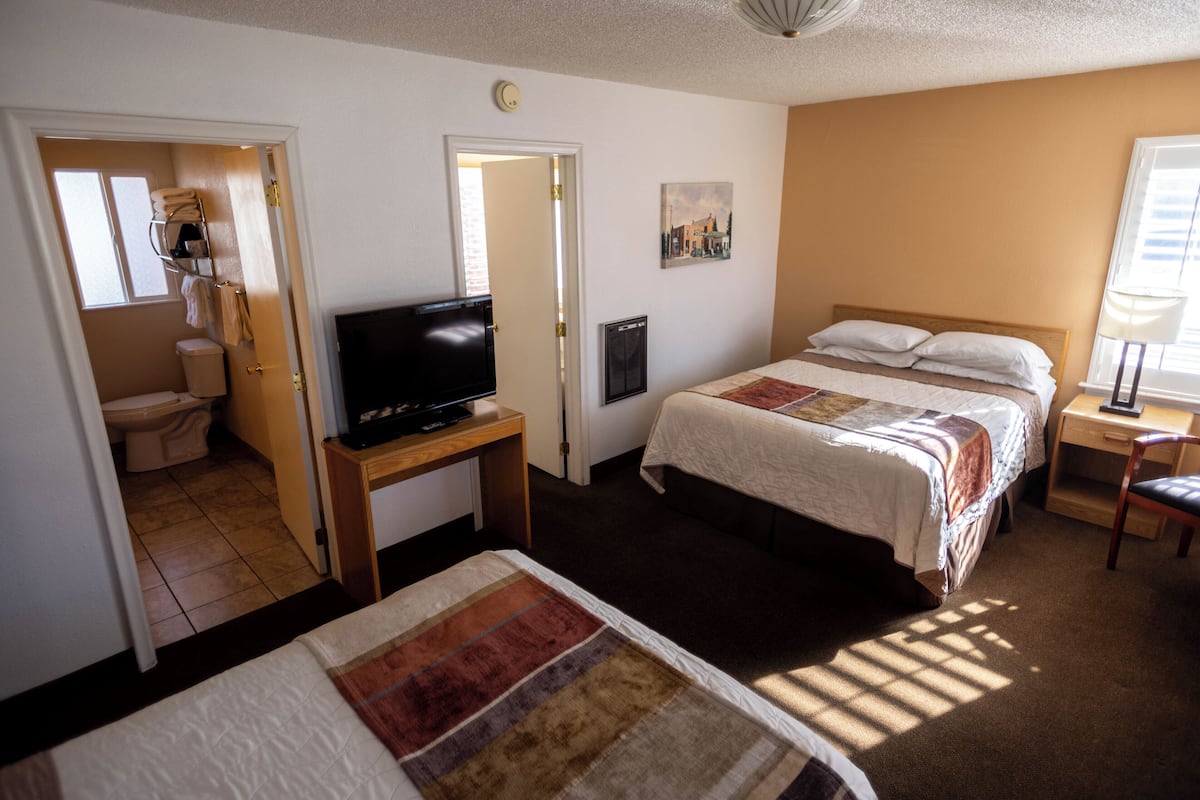 A hotel room with a bed, a television on a stand, a desk, and a window.