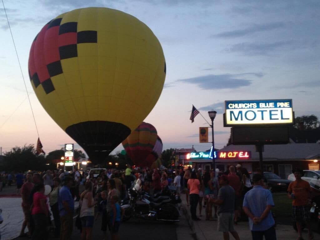 A busy street scene with a large yellow hot air balloon and a motel sign.