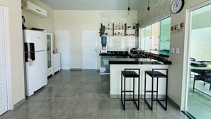 A modern kitchen with a central island, bar stools, and a clock on the wall.