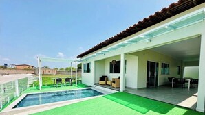 A modern house with a swimming pool, outdoor seating, and a covered patio.