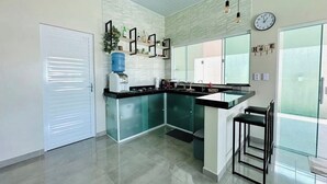A modern kitchen with a central island, a water dispenser, and a clock on the wall.