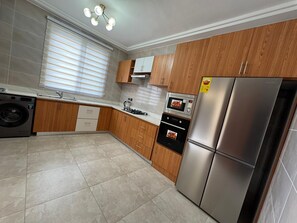 A modern kitchen with wooden cabinets, stainless steel appliances, and a built-in washer.