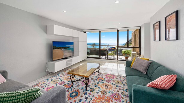 A modern living room with a flat-screen TV, a sofa, a coffee table, and a colorful rug. - 6 58 Pacific Drive Port Macquarie (Port Macquarie)