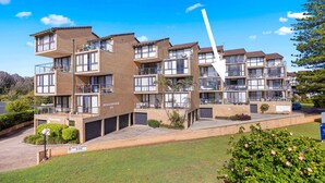 A multi-story residential building with balconies, a parking area, and a sign indicating no parking on grass. - 6 58 Pacific Drive Port Macquarie (Port Macquarie)