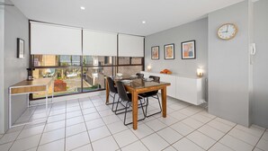 A modern kitchen with a dining area, large windows, and a view of the outside. - 6 58 Pacific Drive Port Macquarie (Port Macquarie)