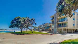 A beachfront residential area with multi-story buildings, a sandy street, and a clear blue sky.