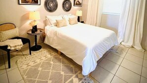 A bedroom with a bed, two bedside tables, a ceiling fan, and a window with curtains.
