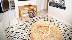A modern living room with a flat-screen TV, a wooden coffee table, a large painting, and a patterned rug.