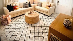 A living room with two sofas, a coffee table, a patterned rug, and a ceiling fan.