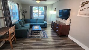 Una sala de estar con un sofá modular, una mesa de centro de madera, un televisor y una estantería.