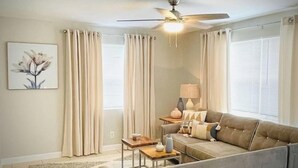 A living room with a sofa, a coffee table, a lamp, and a ceiling fan.