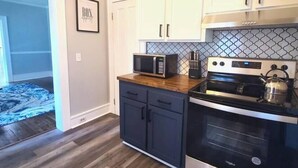 A kitchen with white cabinets, a microwave, a stove, and a tiled backsplash.