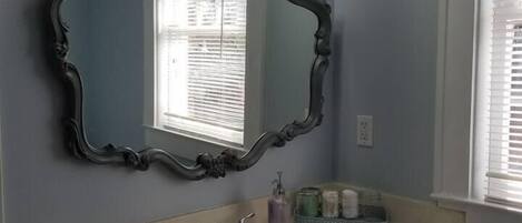 A bathroom with a vanity, a large mirror, and three wall-mounted lights.