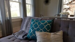 A gray sofa with patterned cushions and a decorative wall piece. - 10 Historic Earle with Rustic Charm (Greenville)