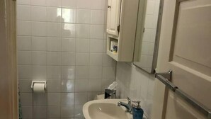Uma casa de banho pequena com sanita, lavatório e espelho.
