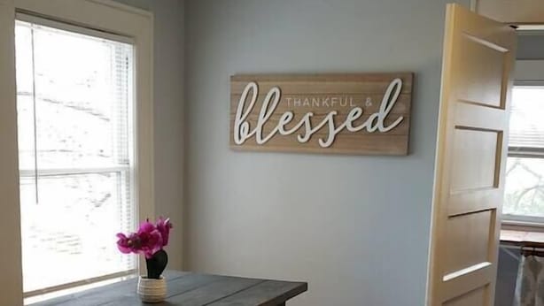 Un comedor con una mesa de madera, dos taburetes y un letrero en la pared que dice 'blessed'.
