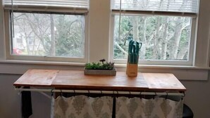 Una habitación con una mesa de madera, un cartel sobre las ventanas y vistas a árboles desde el exterior.
