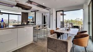 Uma cozinha moderna com uma ilha grande, banquetas de bar e um espaço de refeições com cadeiras.
