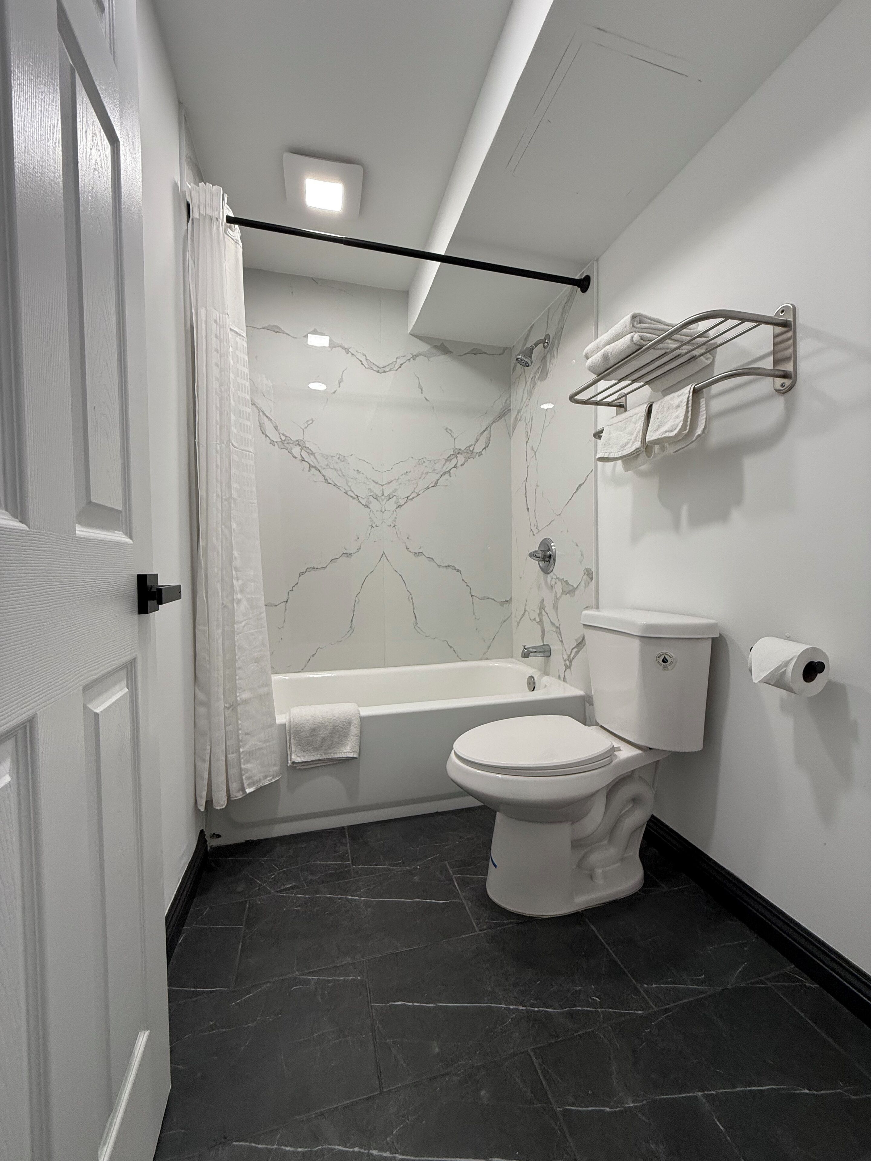 Un baño moderno con inodoro blanco, bañera y zona de ducha.