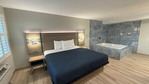 Egy modern hálószoba, melyben egy nagy ágy, éjjeliszekrények, beépített éjjeliszekrény, falra szerelt lámpa található, a fürdőszobában pedig márványburkolat és fürdőkád van.