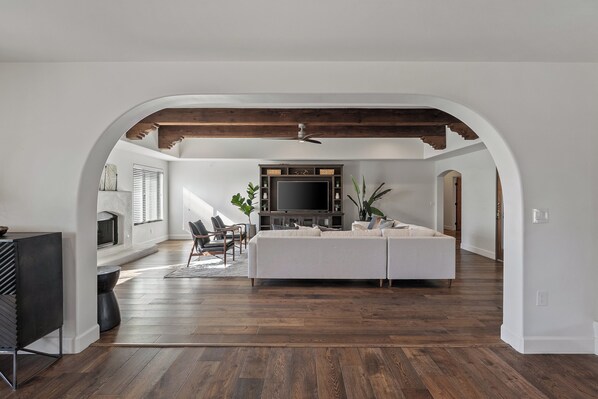 Relax in a spacious living area with a high ceiling and exposed beams, featuring a large TV, comfortable sofa, and coffee table.