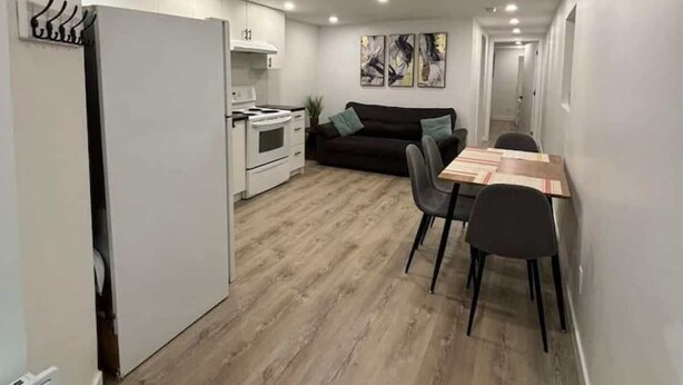 Une cuisine moderne avec des armoires blanches, un four encastré et un coin repas comprenant une table et des chaises en bois.