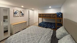 Une chambre avec des lits superposés, une commode, une armoire et deux œuvres d’art accrochées au mur.