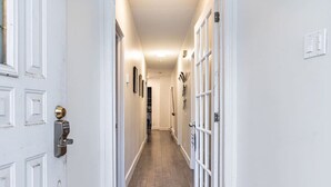 Un pasillo con paredes blancas, suelo de madera y una puerta con tirador de latón.