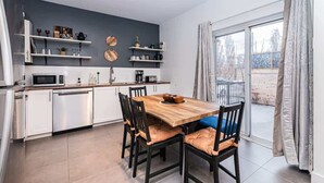 Una cocina moderna con armarios blancos, una mesa de comedor de madera y un microondas empotrado.