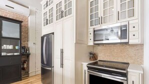 A kitchen with white cabinetry, a stainless steel refrigerator, a microwave, and an oven.