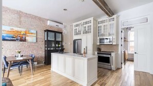 A modern kitchen with white cabinetry, a central island, and a dining area with a table and chairs.