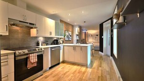 A modern kitchen with a central island, built-in oven, and stainless steel appliances.