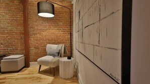 A room with a brick wall, a white sofa, a small round table, and a hanging lamp.