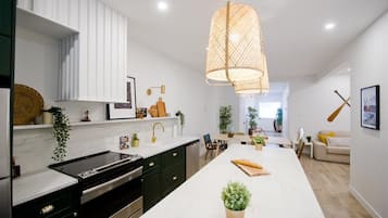 A modern kitchen with a central island, dark cabinetry, and a hanging light fixture.