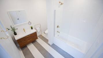 A bathroom with a white vanity, a mirror, a towel rack, a shower with a glass door, and a patterned floor.
