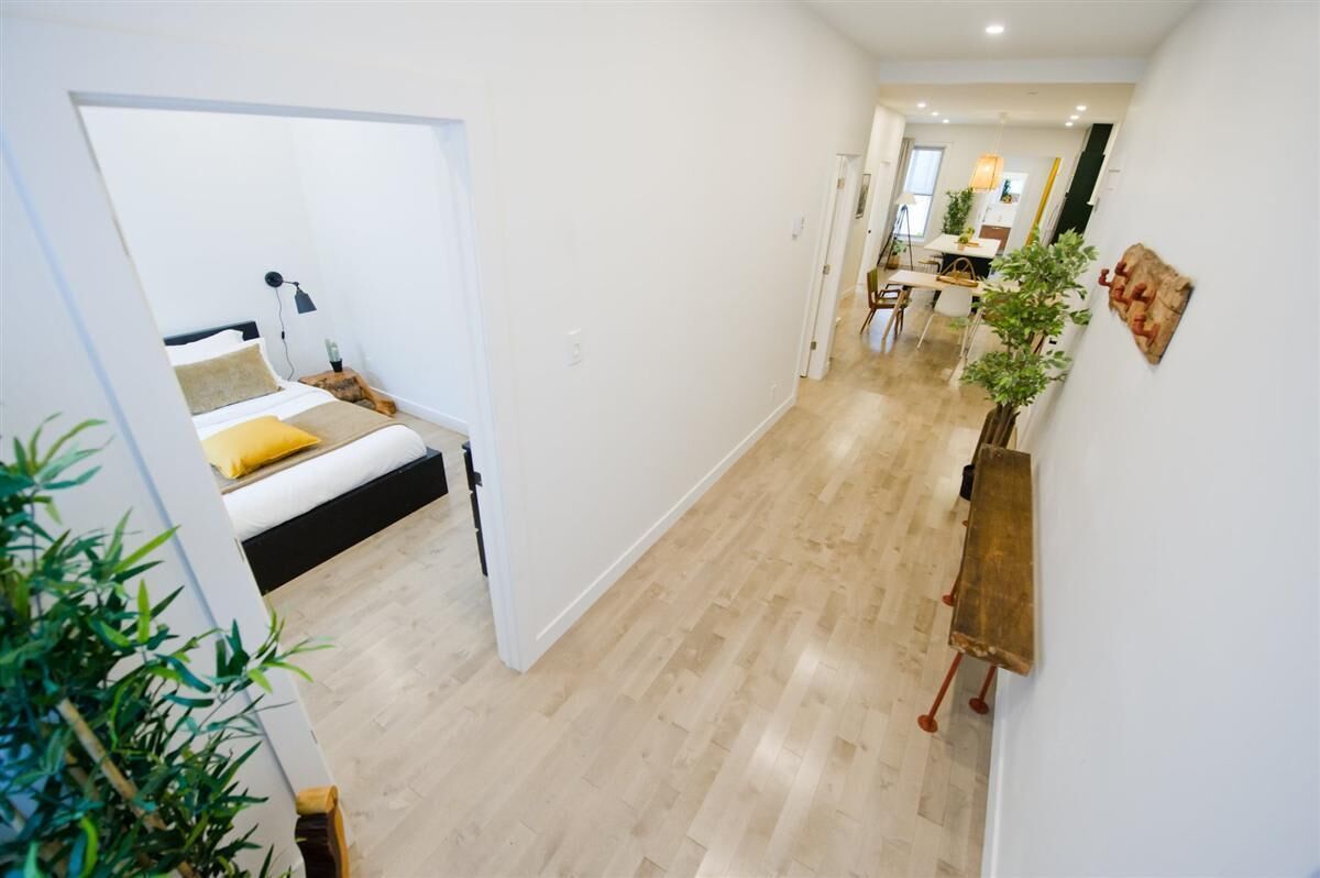 A modern interior with a bed, a dining area, and a hallway.
