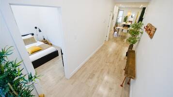 A modern interior with a bed, a dining area, and a hallway.