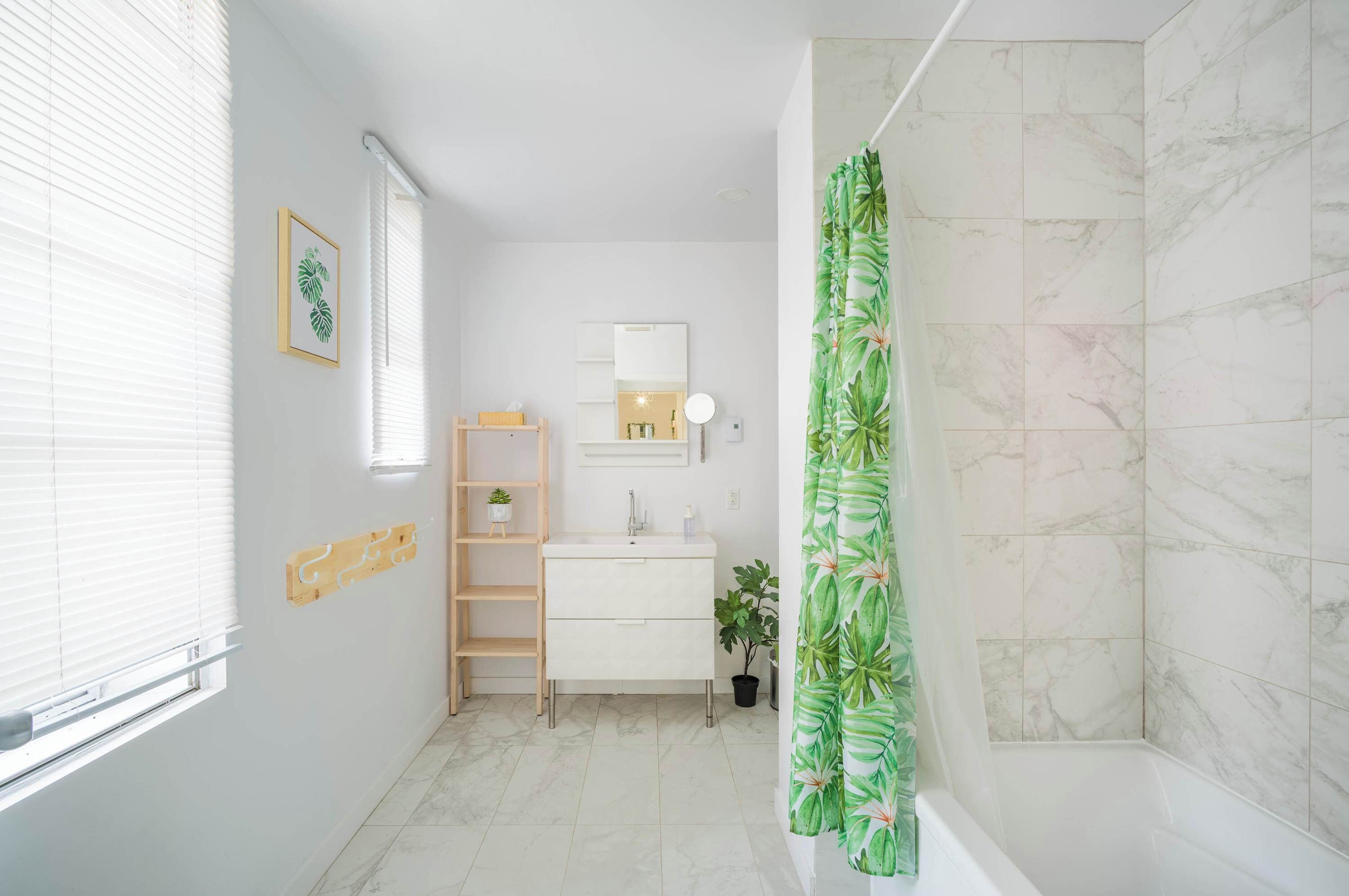 A bathroom with a shower, a sink, a mirror, and a window.