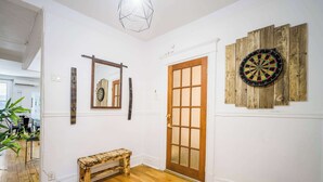 A hallway with a wooden bench, a door, a mirror, and a dartboard. - Trendy 4BR Montreal Home Perfect for Groups (Montréal)