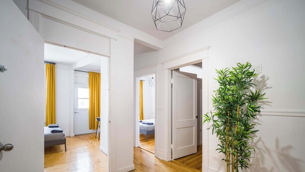 A hallway with wooden flooring, white walls, and a potted plant. - Trendy 4BR Montreal Home Perfect for Groups (Montréal)