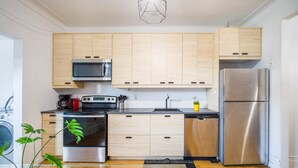 A modern kitchen with wooden cabinets, stainless steel appliances, and a glass table. - Trendy 4BR Montreal Home Perfect for Groups (Montréal)