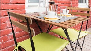 A red brick exterior wall, a white window, a wooden table with chairs, and a coffee maker. - Walk to Olympic Stadium |Modern Montreal Stay - apartment (Montréal)